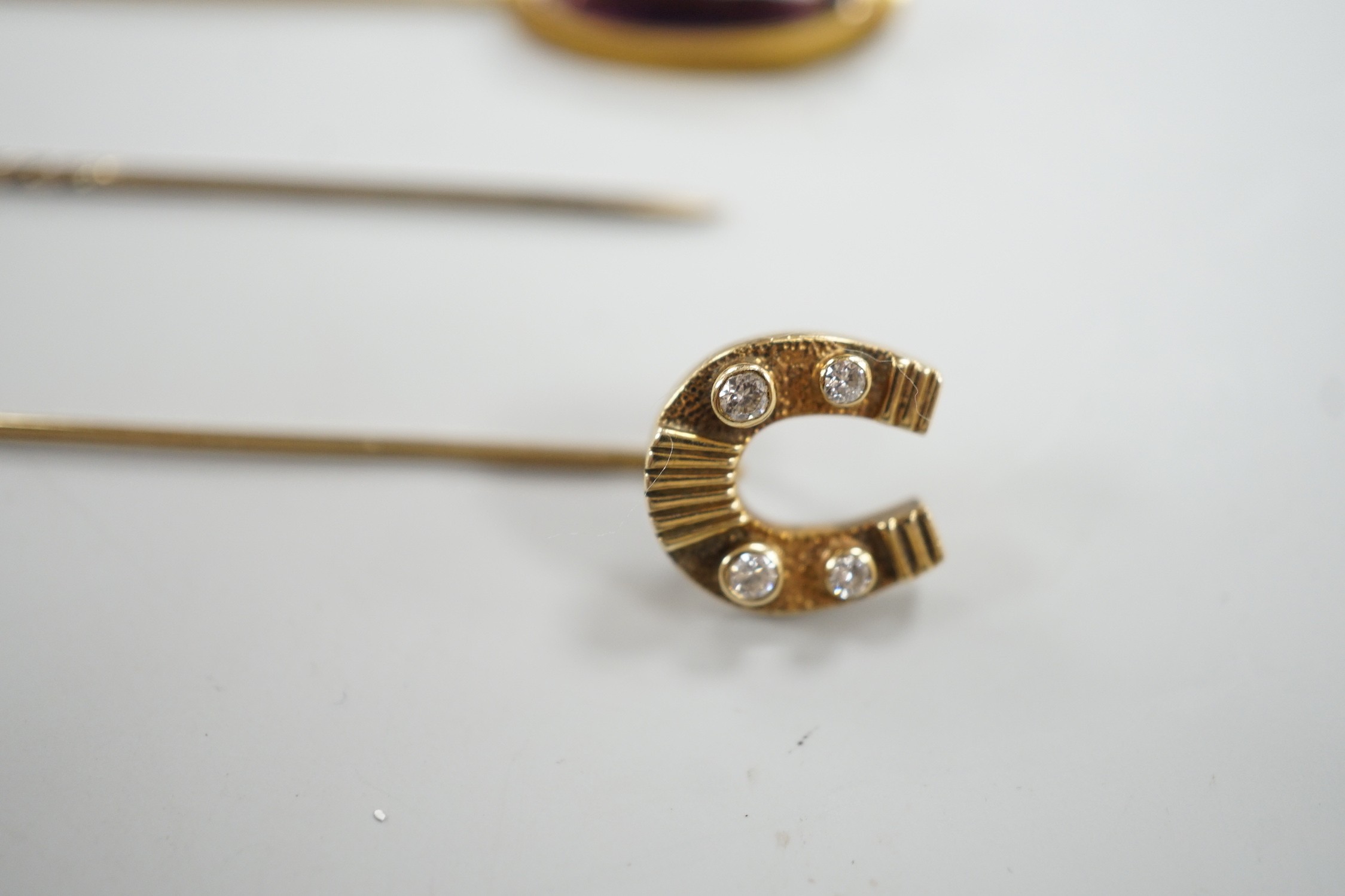 Three assorted yellow metal and gem set stick pins, including 9ct gold and diamond set horseshoe, 58mm and a modern 9ct gold and gem set bar brooch, gross weight 9.2 grams.